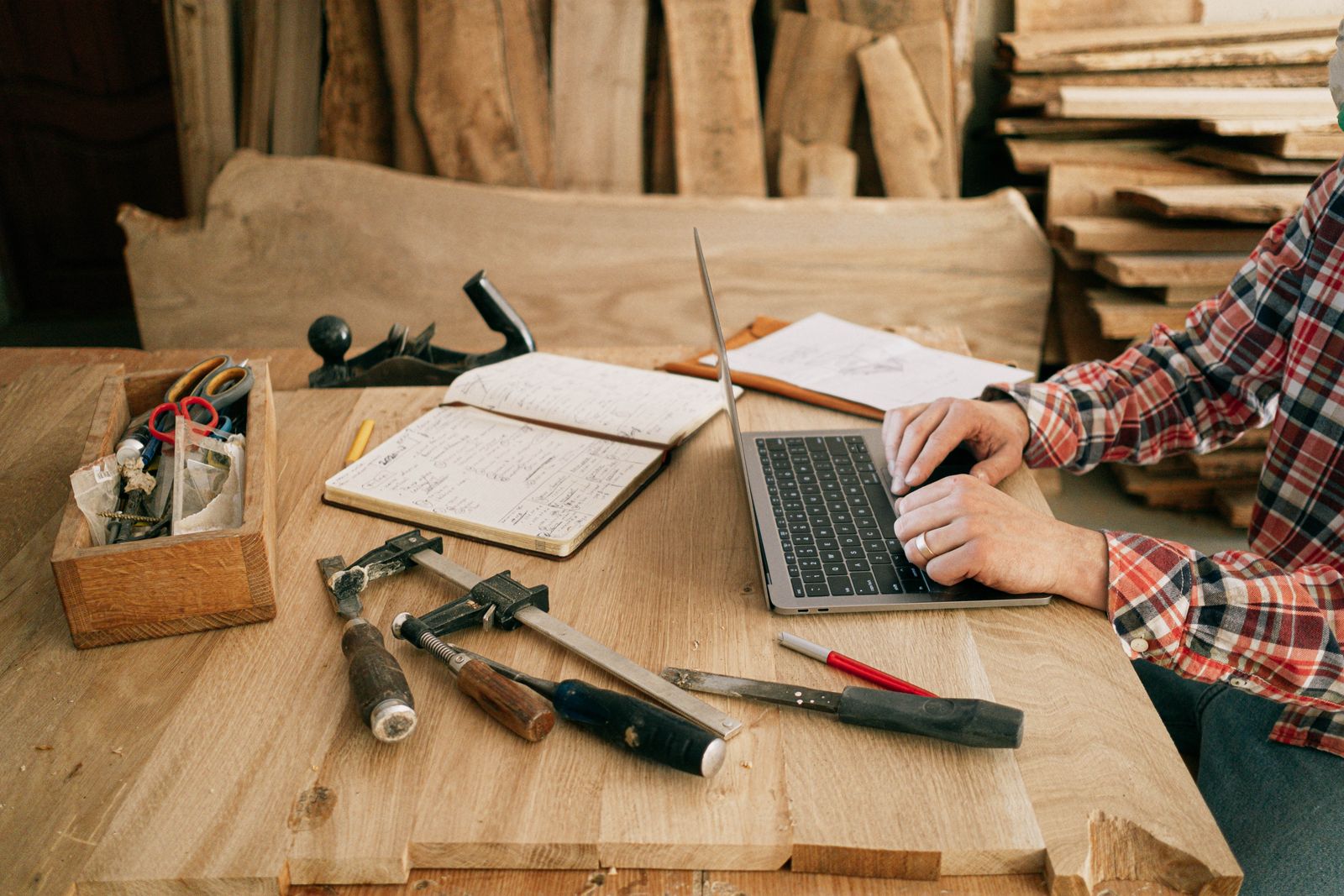 Artisan menuisier gérant sa facturation électronique sur un ordinateur portable dans son atelier