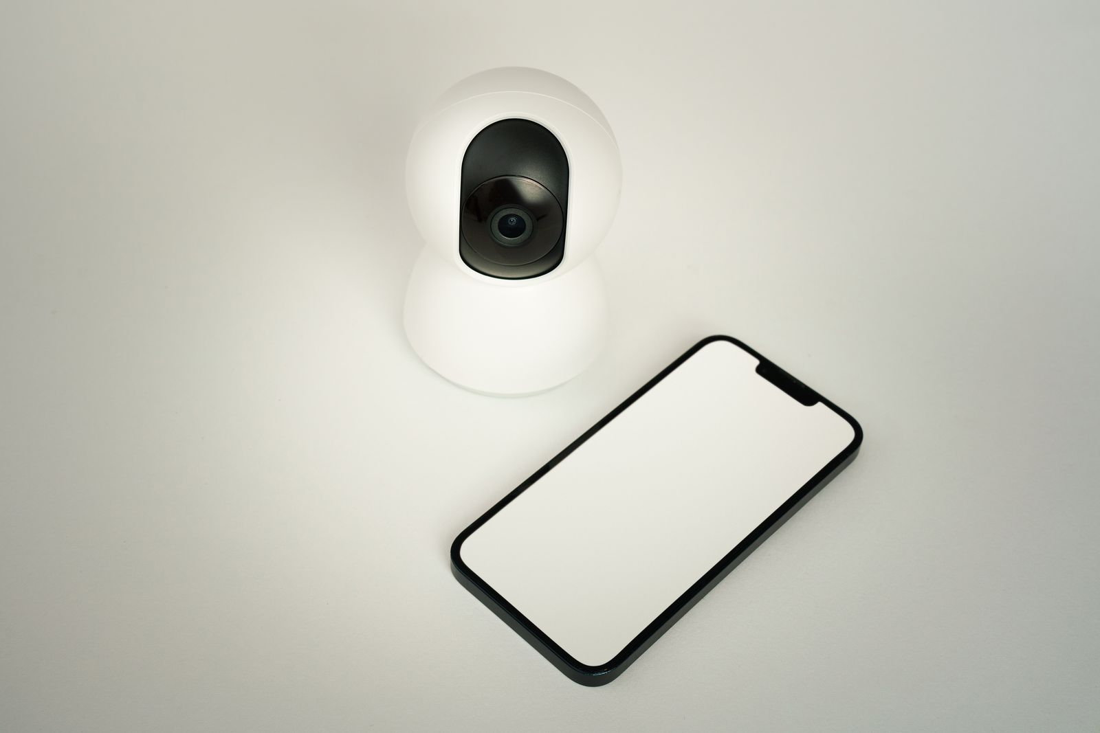 Caméra connectée et smartphone posés sur un plan de travail, illustrant le débit internet nécessaire à une sonnette vidéo
