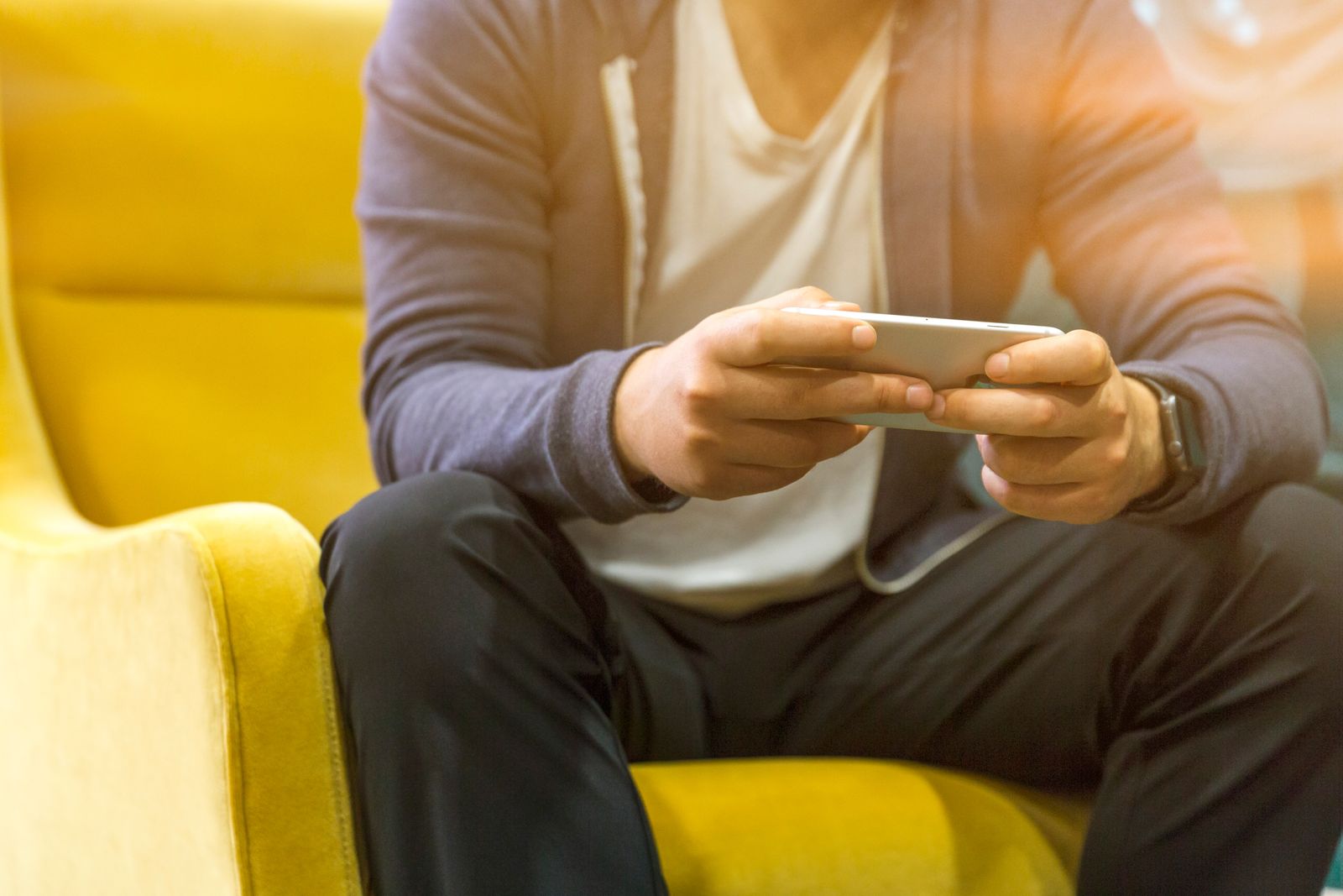Patient assis dans un fauteuil de salle d'attente utilisant son smartphone grâce au Wi-Fi du cabinet
