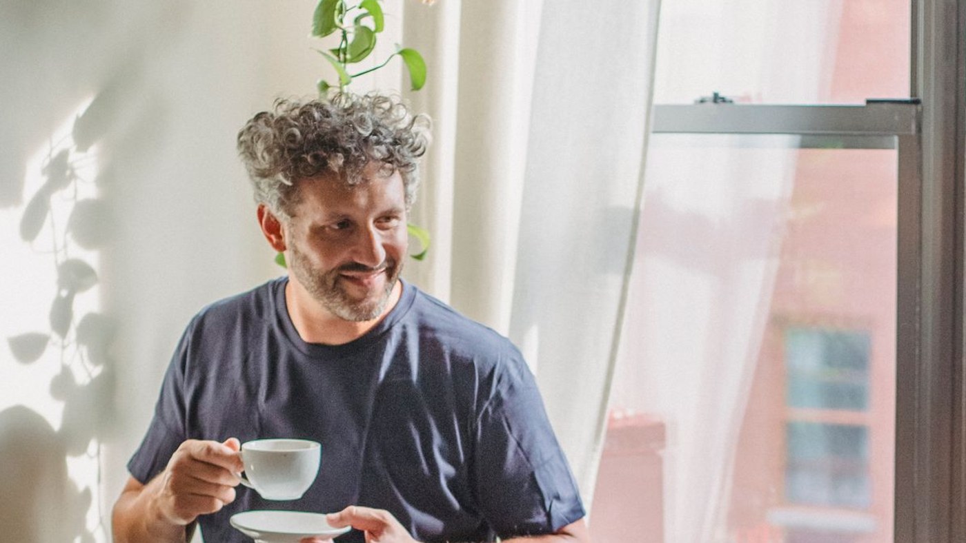 Homme vivant seul chez lui, tasse de café à la main, dans un appartement connecté en box 5G sans fibre