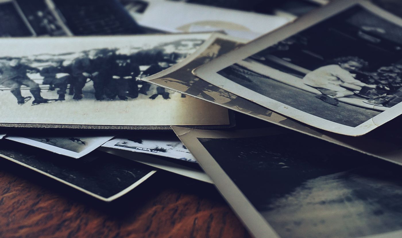 Photographies de famille anciennes en noir et blanc étalées sur une table en bois, à numériser pour une recherche généalogique