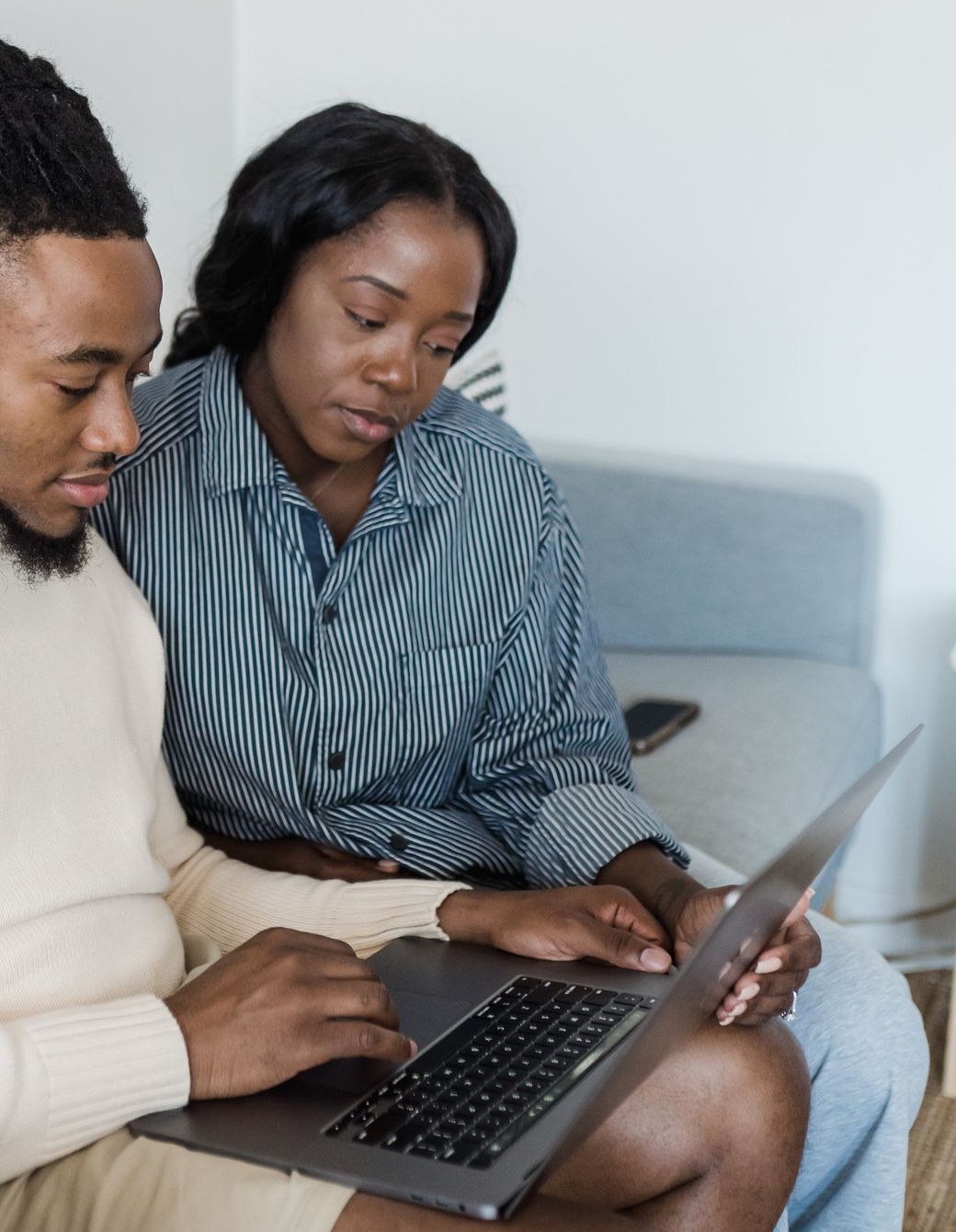 Couple d'acheteurs testant une visioconférence sur ordinateur portable dans un salon connecté par box 5G