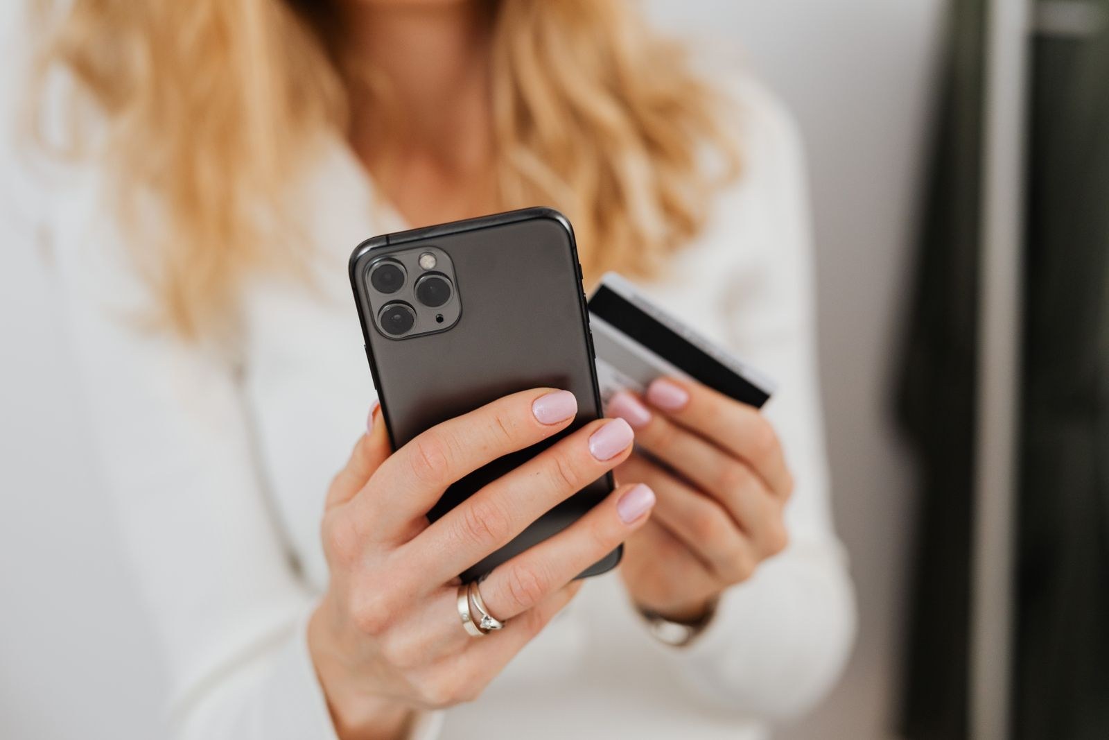 Femme validant un paiement en ligne avec sa carte bancaire et son smartphone, connexion box 5G stable à la maison