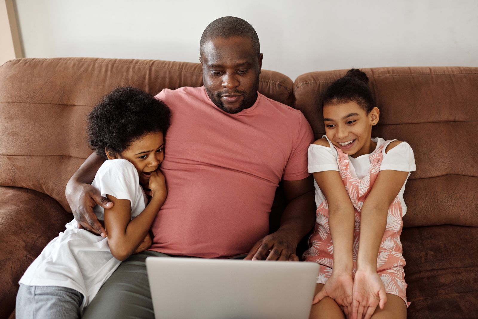 Une famille réunie sur un canapé devant un ordinateur portable, qui utilise un assistant IA avec une connexion box 5G à la maison