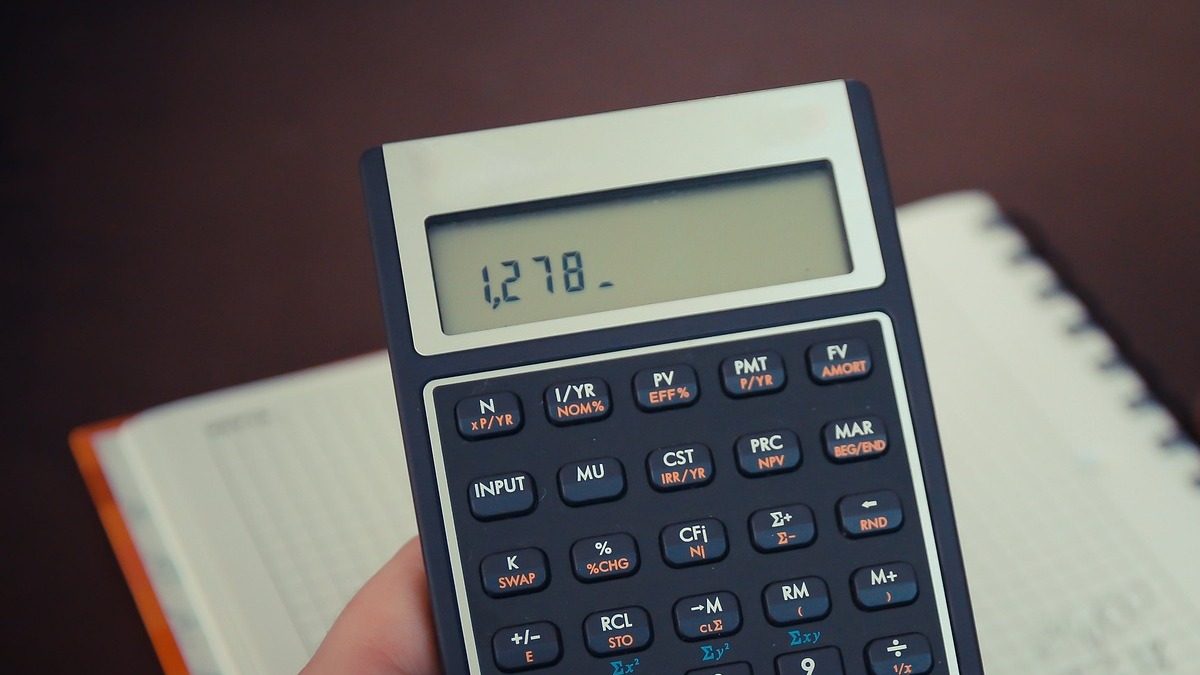 Calculatrice financière posée sur un carnet de comptes pour calculer le coût réel de sa facture internet sur 24 mois