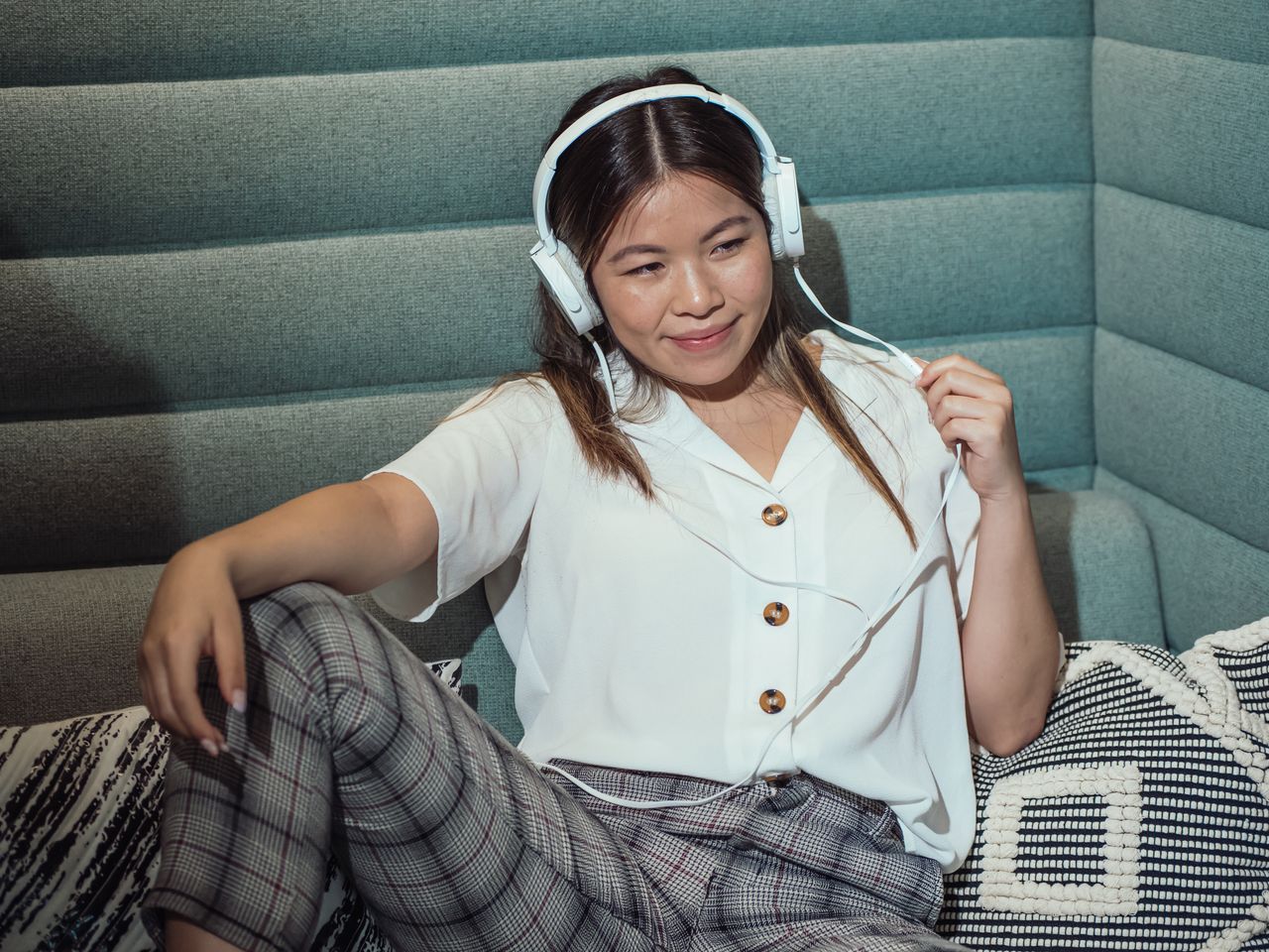 Femme qui écoute de la musique au casque dans un salon lumineux, connectée au Wi-Fi d'une box 5G