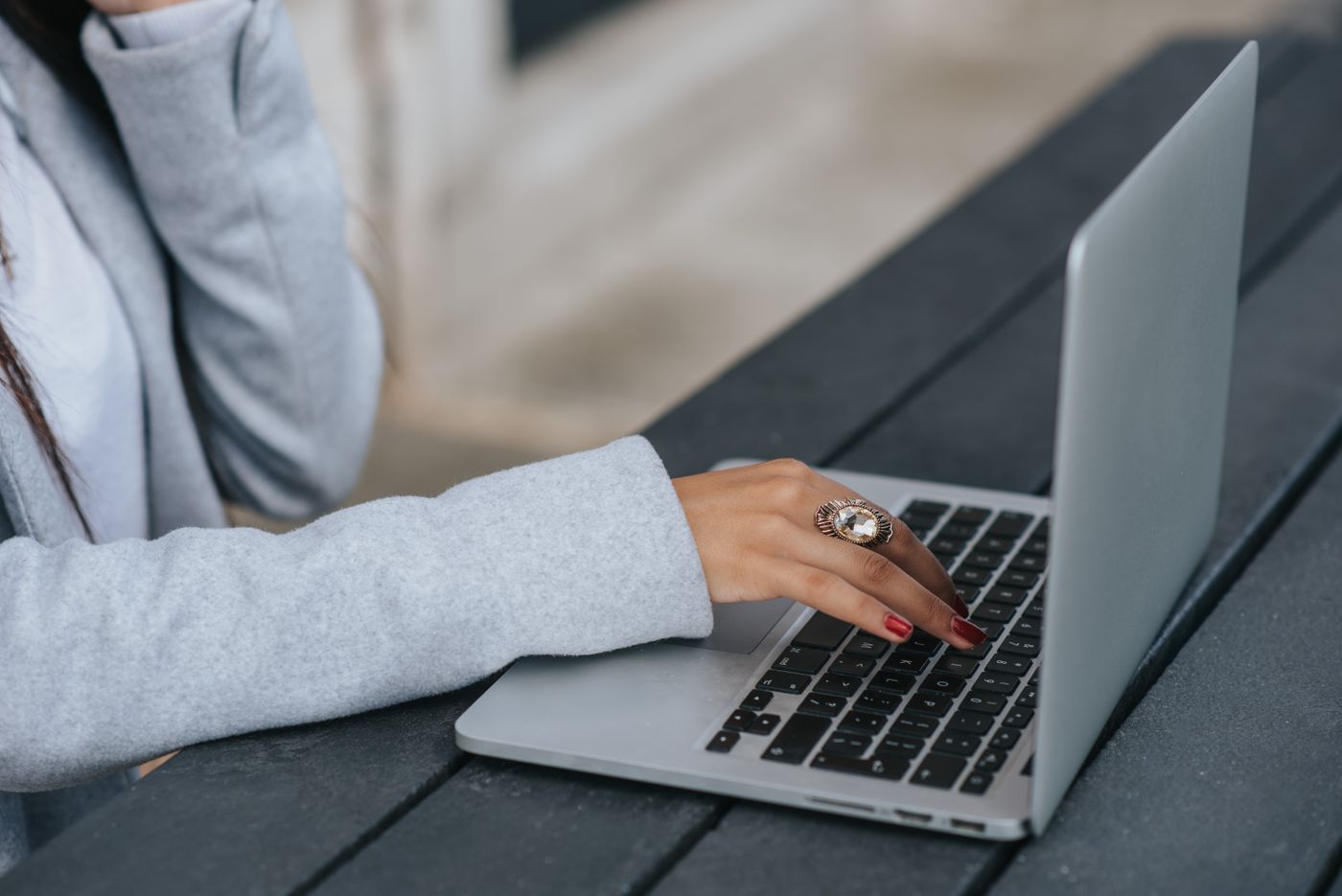 Une personne tape sur un ordinateur portable à une table extérieure, comme au club-house